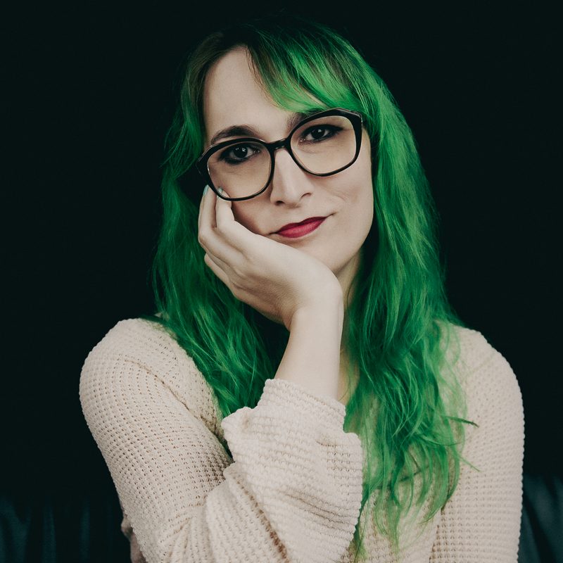 A woman with big glasses and green hair